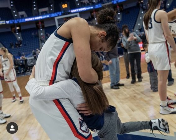 honorary cheer team member gives a huge hug to Uconn player following a win