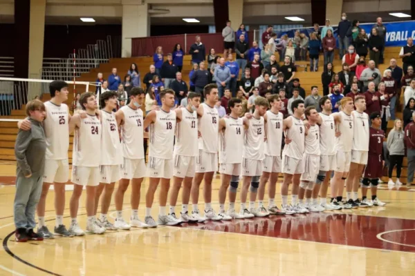 Springfield men's volleyball team gathers together, arm in arm, on the court for a photo